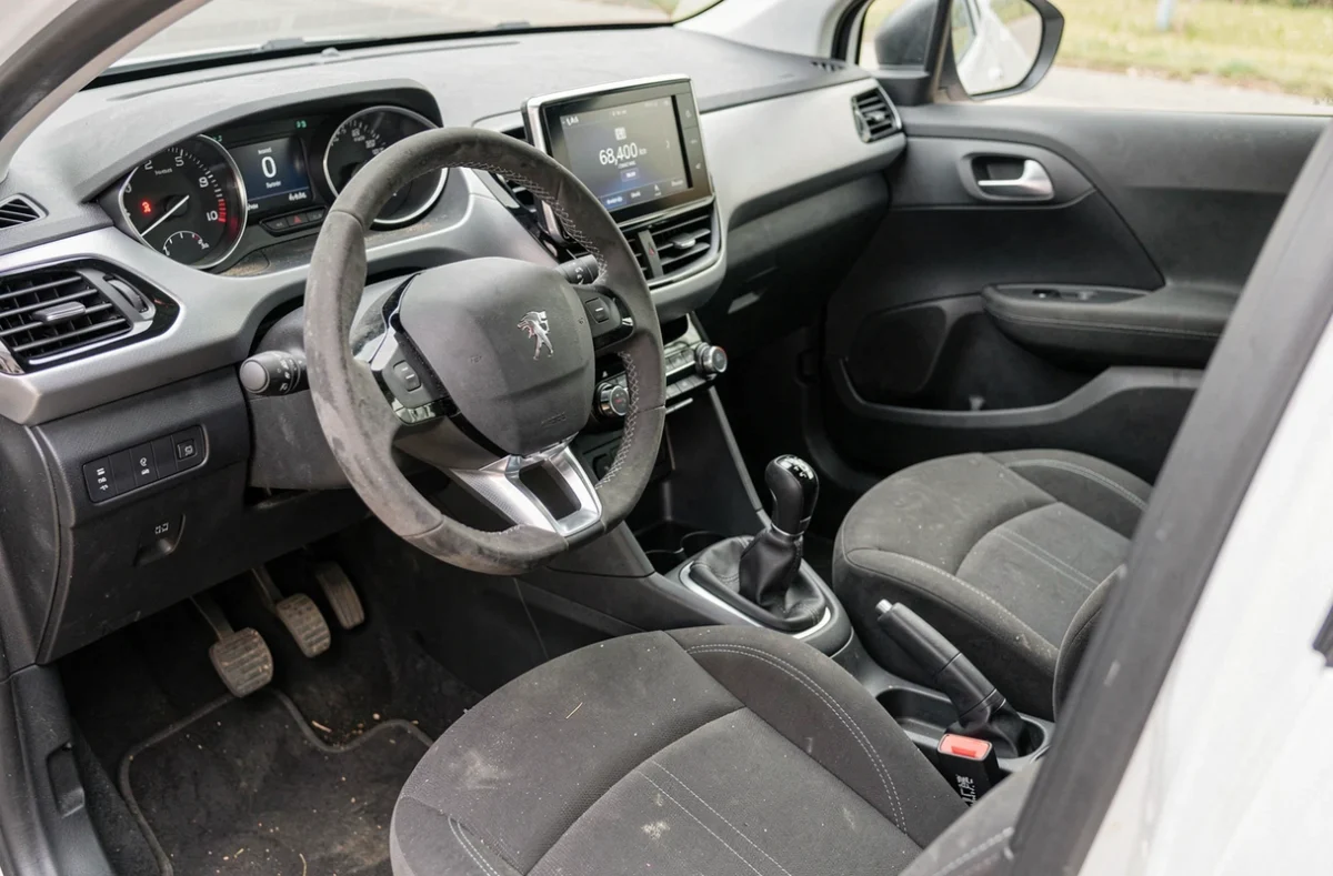 Intérieur usagé d'une Peugeot 208 PureTech avec compteur kilométrique visible pour évaluation de la cote de revente