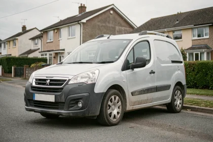 Peugeot Partner Tepee gris garé dans une rue résidentielle, vue trois quarts avant montrant ses proportions utilitaires et sa carrosserie au quotidien