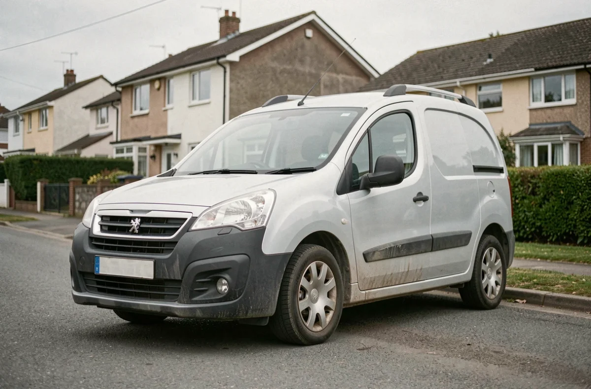 Peugeot Partner Tepee gris garé dans une rue résidentielle, vue trois quarts avant montrant ses proportions utilitaires et sa carrosserie au quotidien