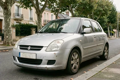 Suzuki Swift 1.3 DDiS argentée avec 200 000 km au compteur garée dans une rue résidentielle française, montrant les traces d'usure réalistes d'un véhicule diesel fiable et vieillissant